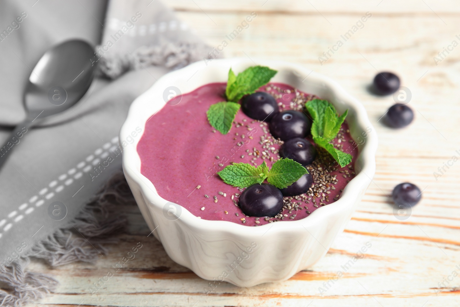 Photo of Bowl with tasty acai smoothie on wooden table