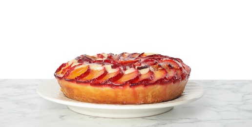 Delicious plum cake on marble table against white background