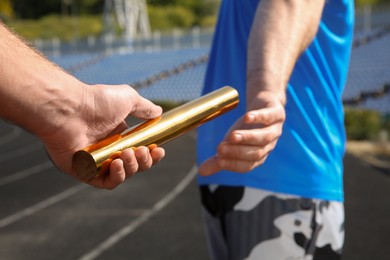 Photo of Man passing baton to his partner at stadium, closeup