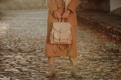 Young woman with stylish beige backpack on city street, closeup