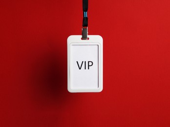 Photo of White plastic vip badge hanging on red background