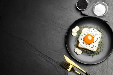 Photo of Tasty toast served with egg, cheese and microgreens on black table, top view. Space for text
