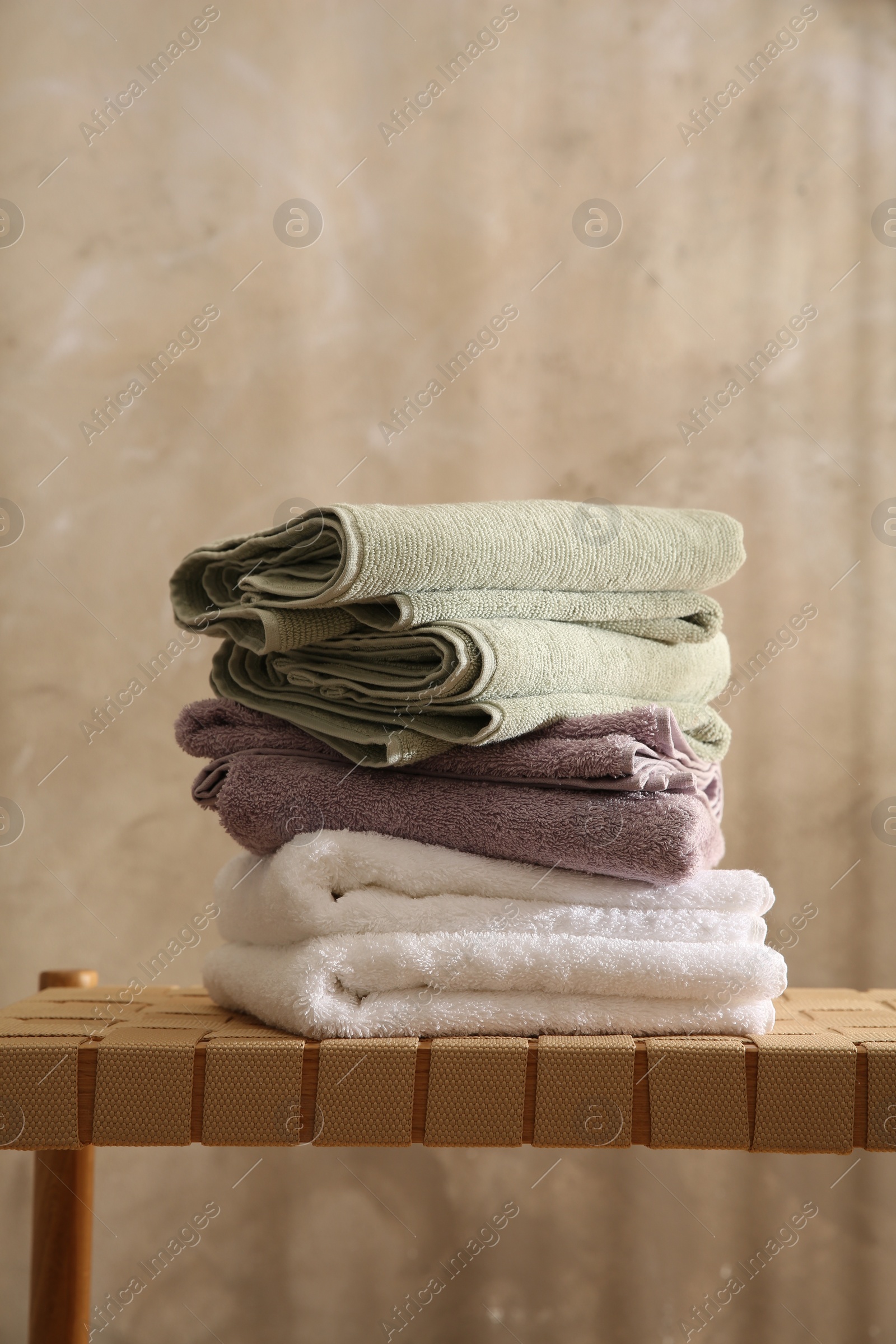 Photo of Stack of soft towels on wicker bench indoors