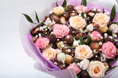 Photo of Beautiful food bouquet of sweets and flowers on light background