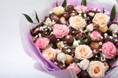 Beautiful food bouquet of sweets and flowers on light background