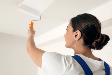 Photo of Worker painting ceiling with white dye indoors