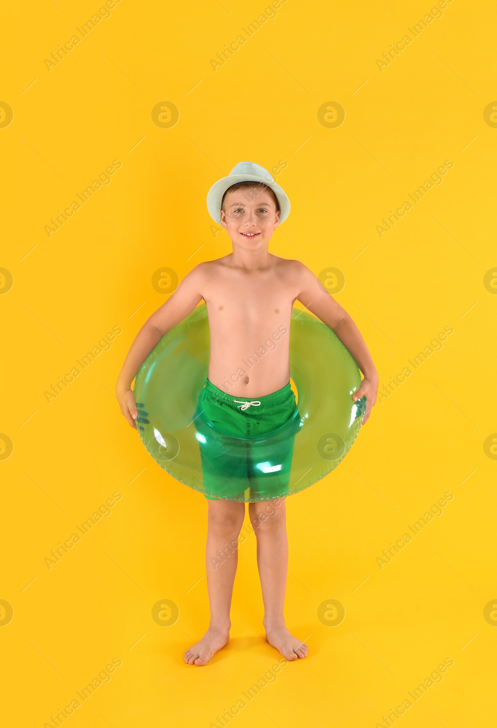 Photo of Cute little child in beachwear with bright inflatable ring on yellow background