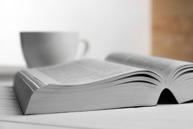 Open Bible on white wooden table indoors, closeup. Religious book