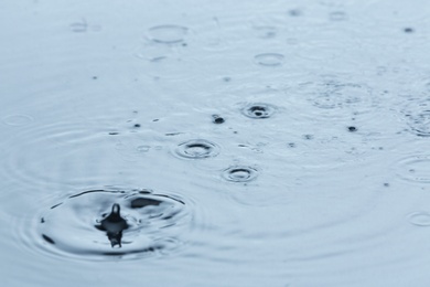 Photo of Rain drops falling down into puddle outdoors