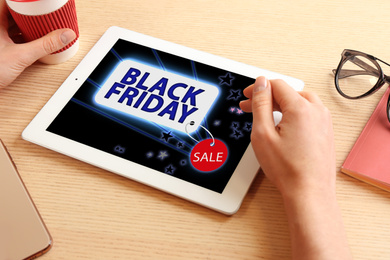 Black Friday. Woman shopping online using tablet at table, closeup