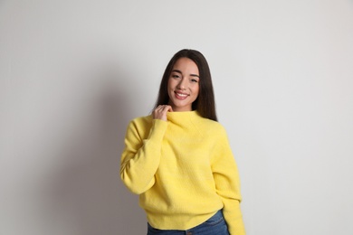 Beautiful young woman wearing yellow warm sweater on white background