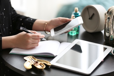 Photo of Female blogger using smartphone at table indoors, closeup