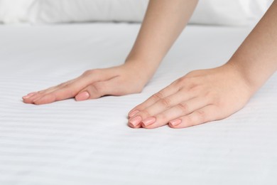 Photo of Woman touching white soft mattress on bed, closeup view