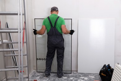 Photo of Worker in uniform taking double glazing window indoors, back view