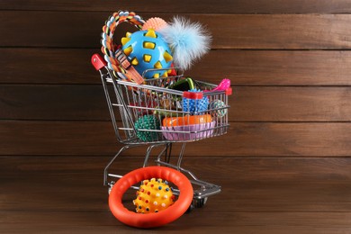 Shopping cart with different pet shop goods on wooden background