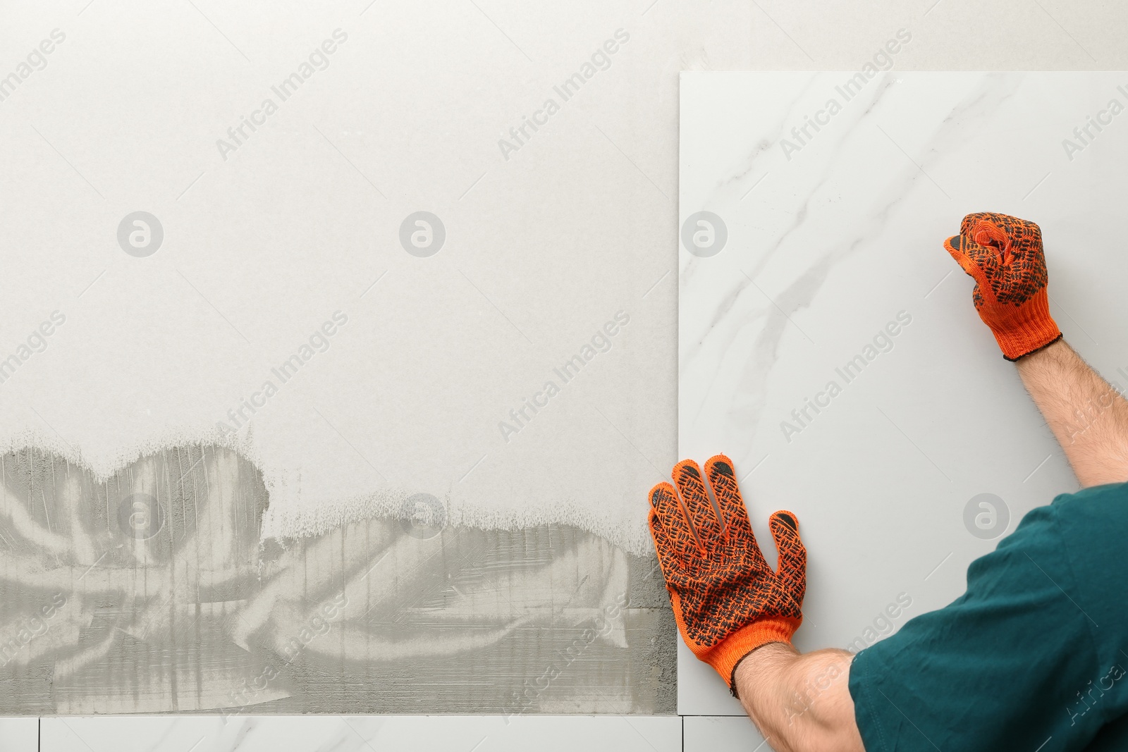 Photo of Man installing ceramic tile on wall, space for text. Building and renovation works