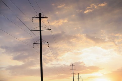 Photo of Telephone poles and wires against blue sky with clouds