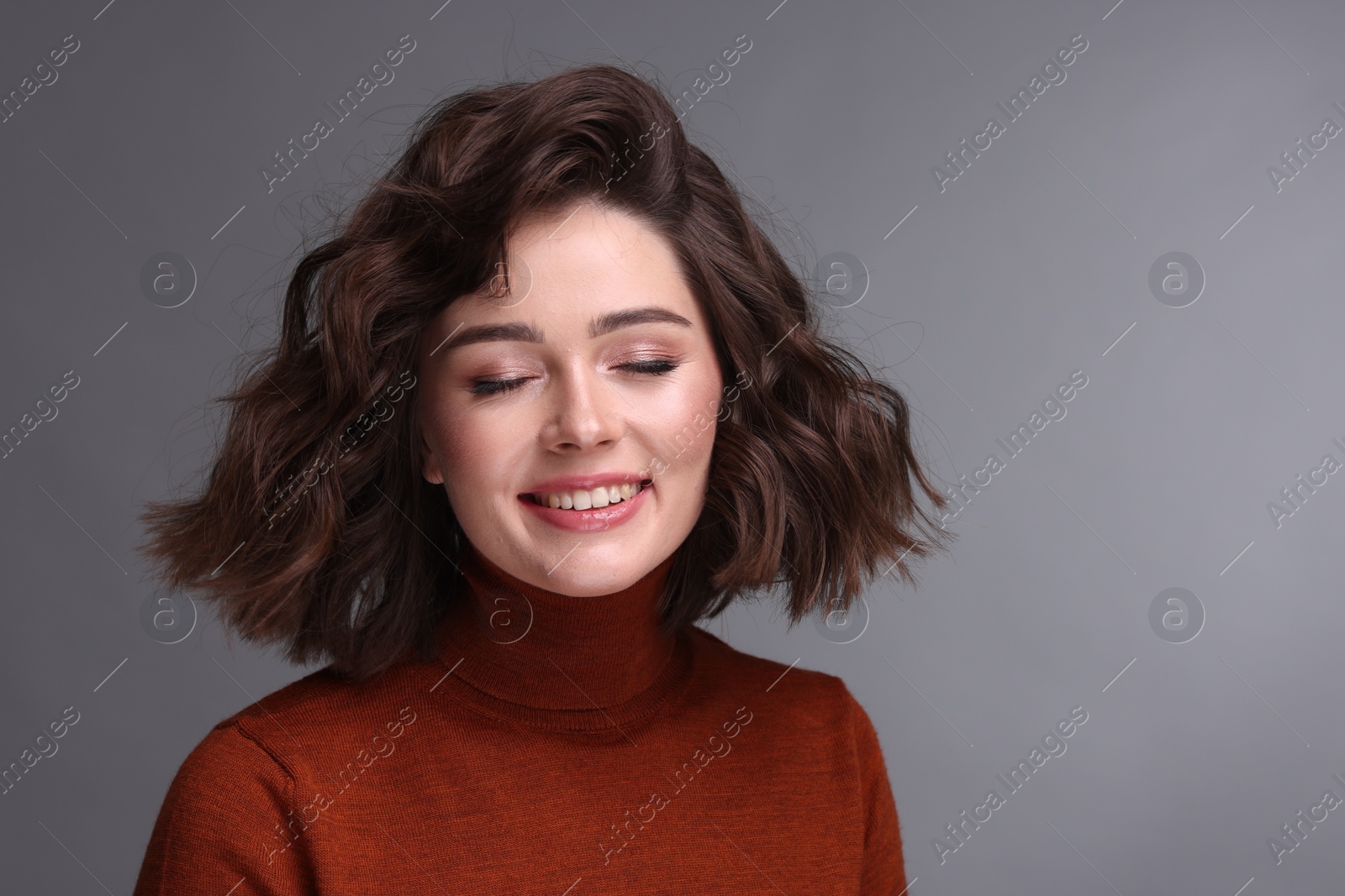 Photo of Portrait of beautiful young woman with wavy hairstyle on grey background. Space for text