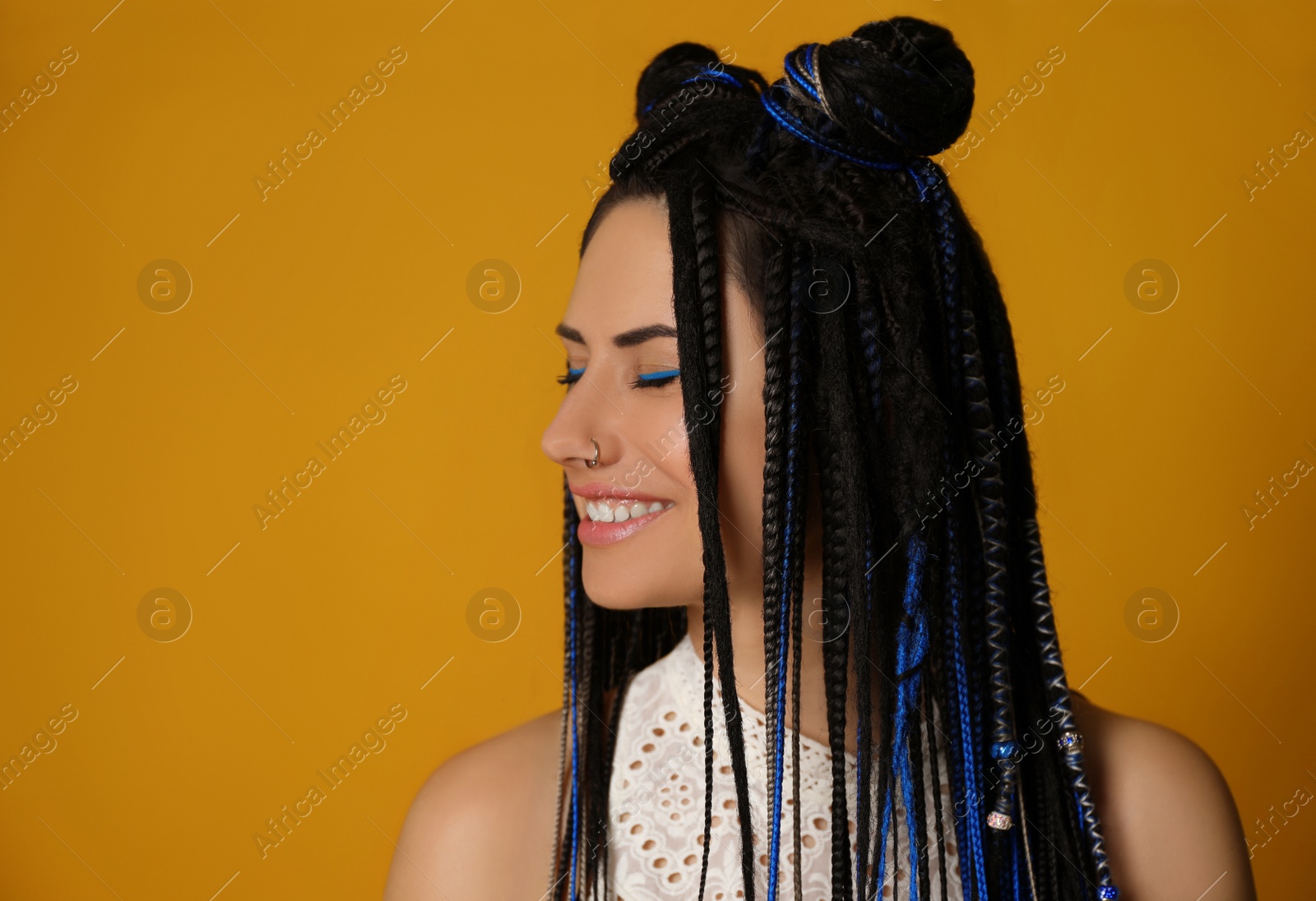 Photo of Beautiful young woman with nose piercing and dreadlocks on yellow background. Space for text