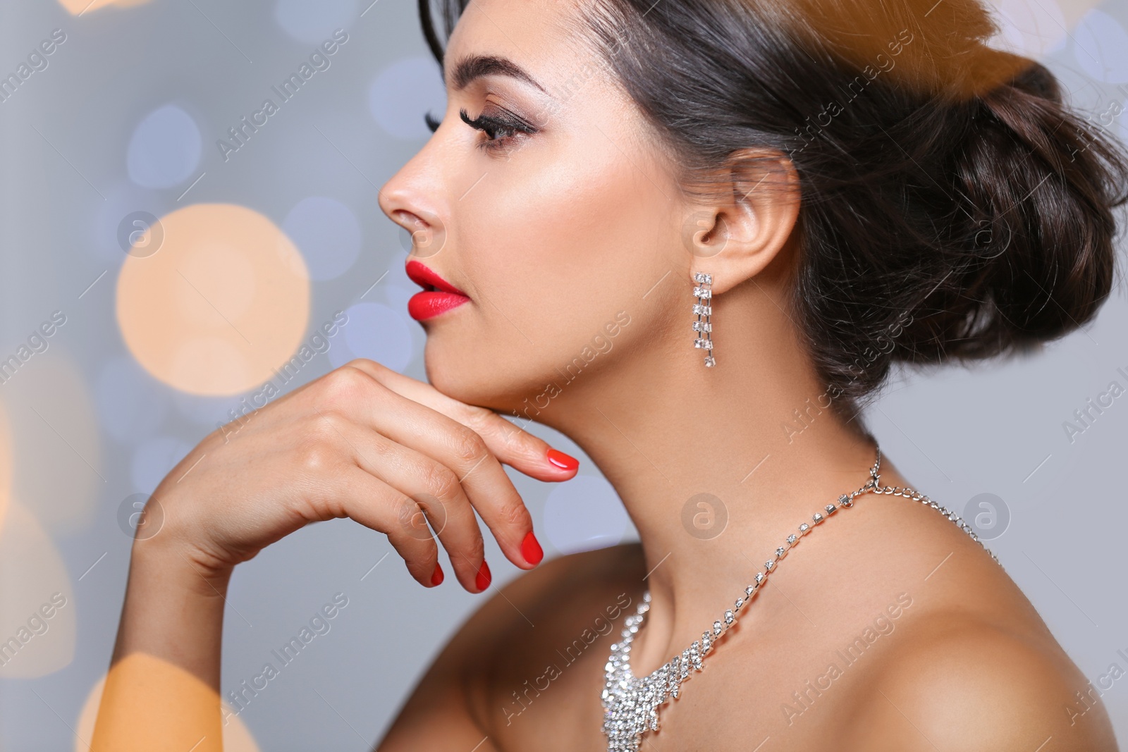 Photo of Beautiful woman with elegant jewelry on blurred background, closeup