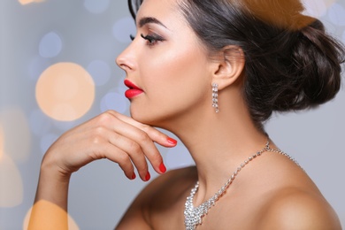 Photo of Beautiful woman with elegant jewelry on blurred background, closeup