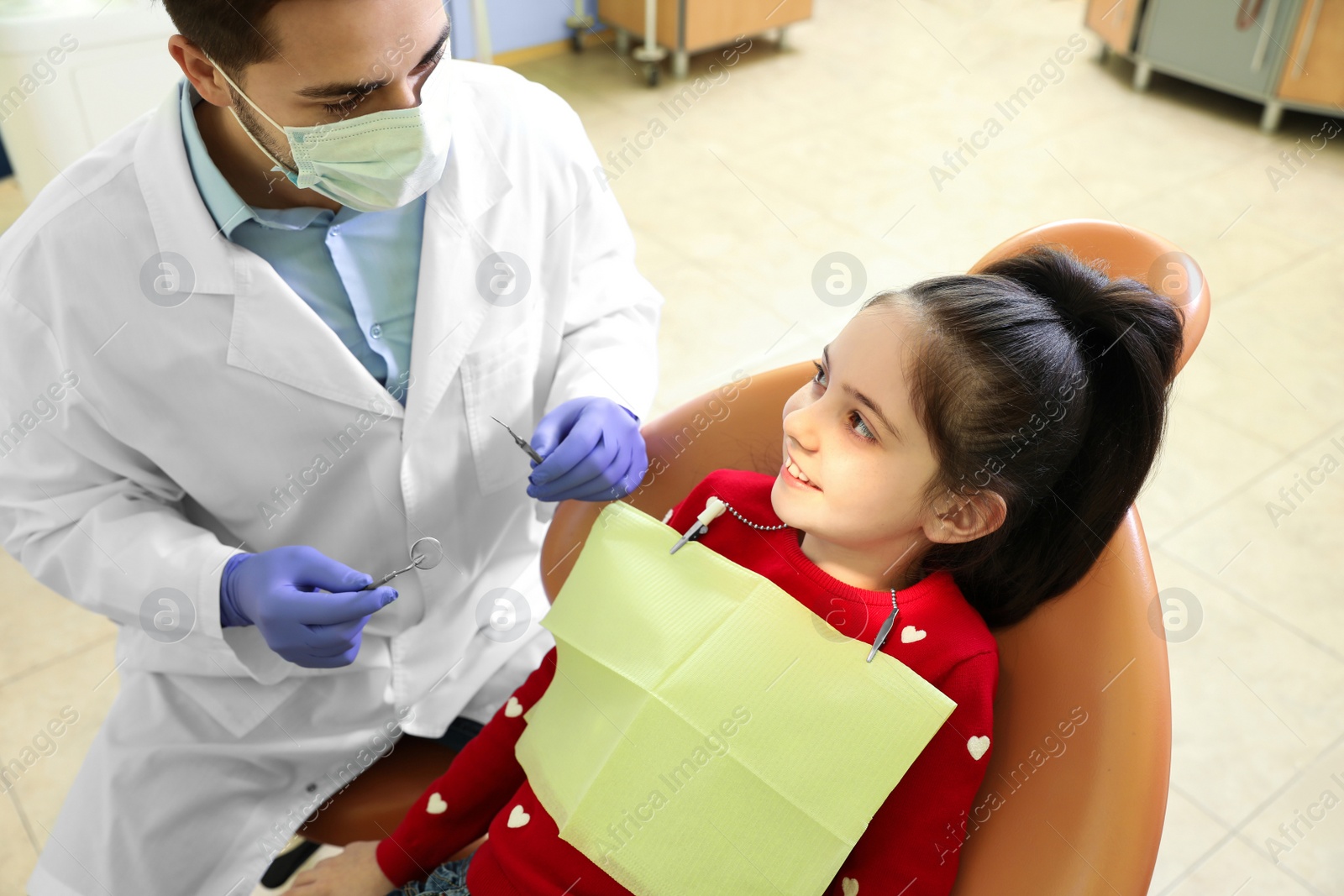 Photo of Professional dentist working with little patient in modern clinic