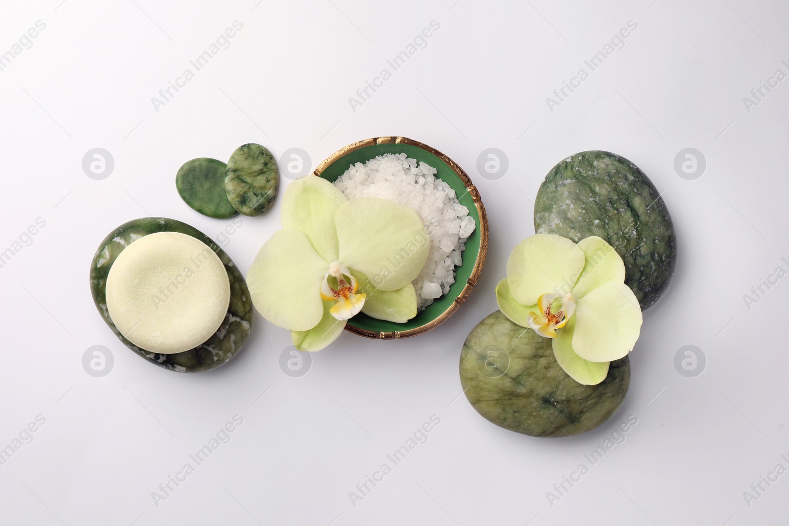 Photo of Flat lay composition with stones, spa products and beautiful flowers on white table