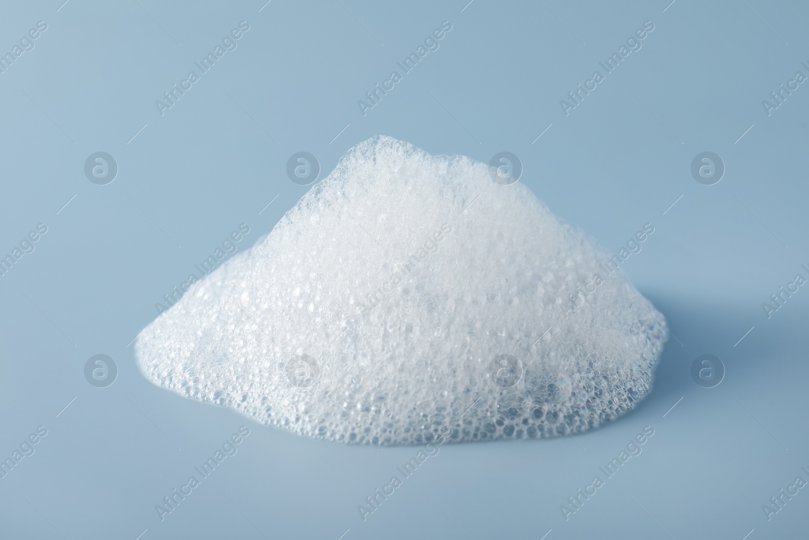 Photo of Drop of fluffy bath foam on light blue background