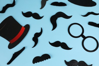 Photo of Fake mustaches, hat and glasses on light blue background