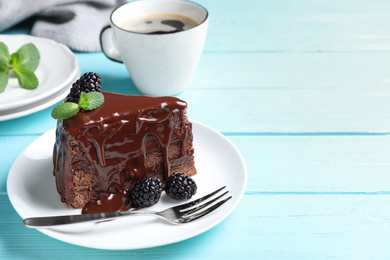 Photo of Delicious chocolate cake with blackberries on light blue wooden table. Space for text