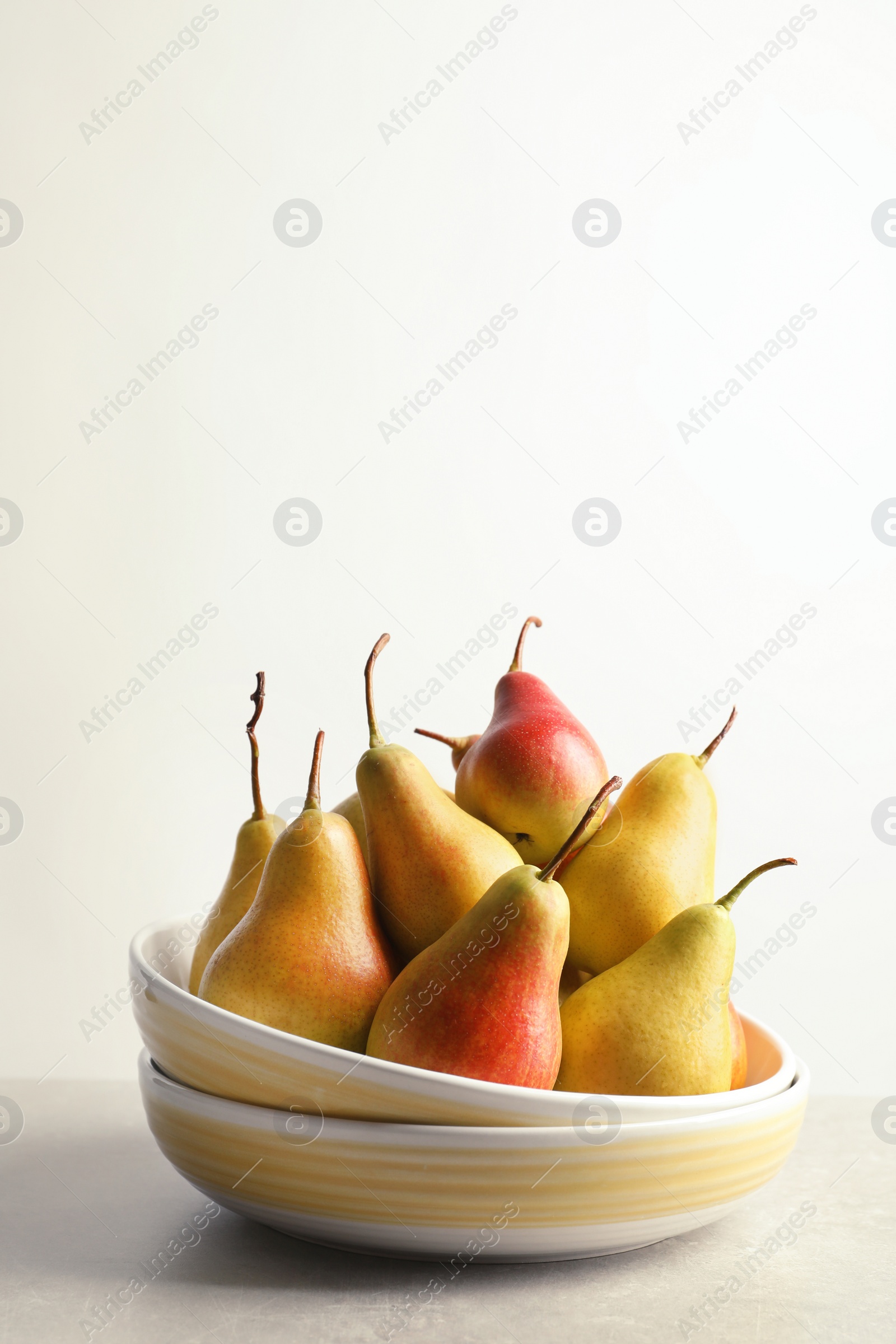 Photo of Plate with ripe pears on table against light background. Space for text