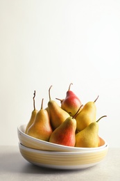 Photo of Plate with ripe pears on table against light background. Space for text