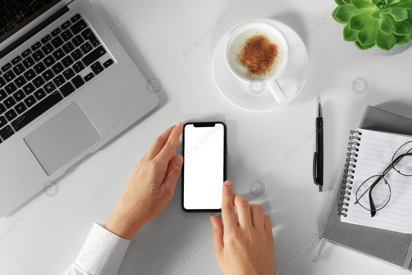 Photo of Woman using smartphone at white table, top view