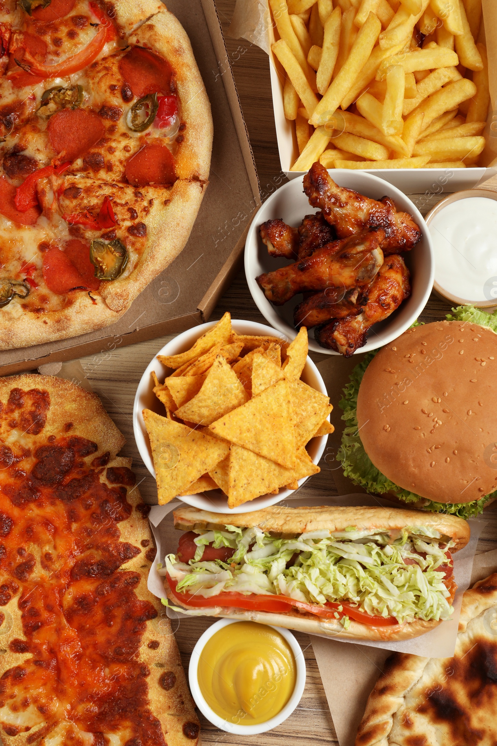 Photo of French fries, pizza and other fast food on wooden table, flat lay