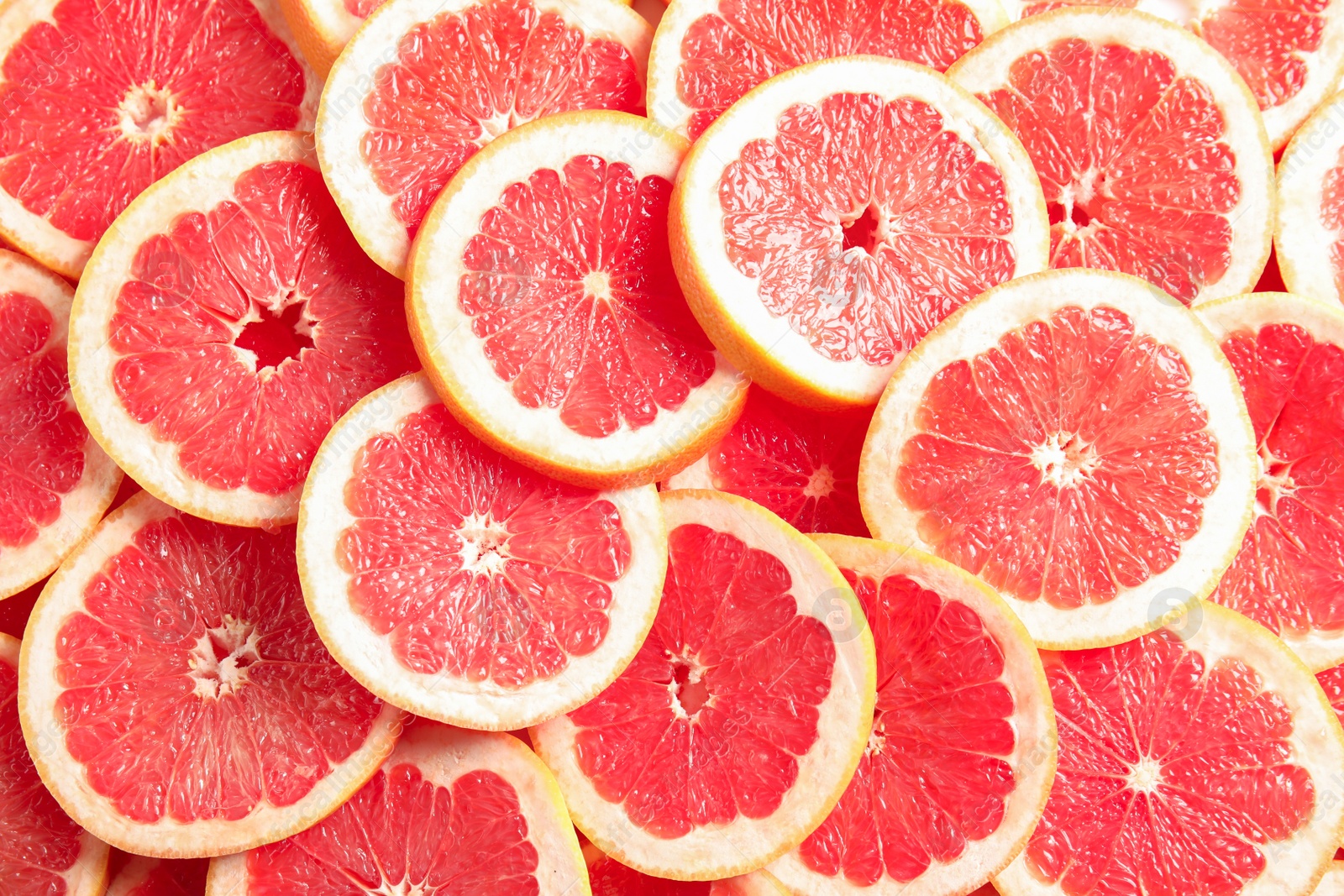 Photo of Many sliced fresh grapefruits as background, top view