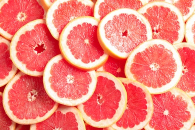 Many sliced fresh grapefruits as background, top view