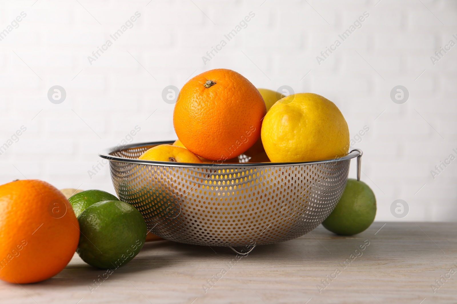 Photo of Different fresh fruits in colander on white wooden table