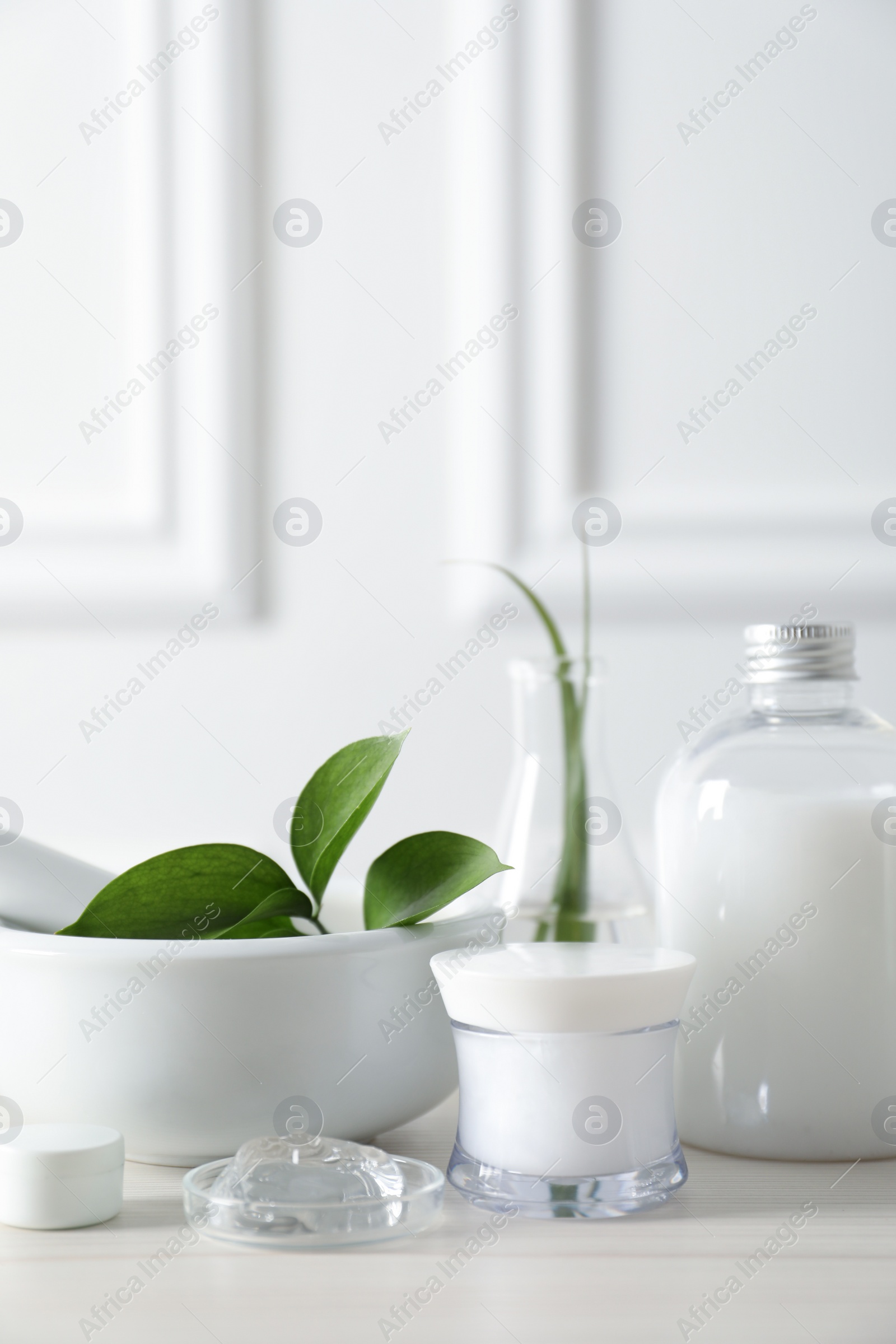 Photo of Natural ingredients for cosmetic products and laboratory glassware on white table