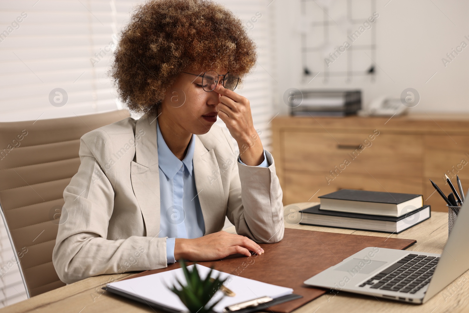 Photo of Woman suffering from headache at workplace in office