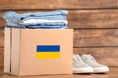 Humanitarian aid for Ukrainian refugees. Donation box with clothes on wooden table