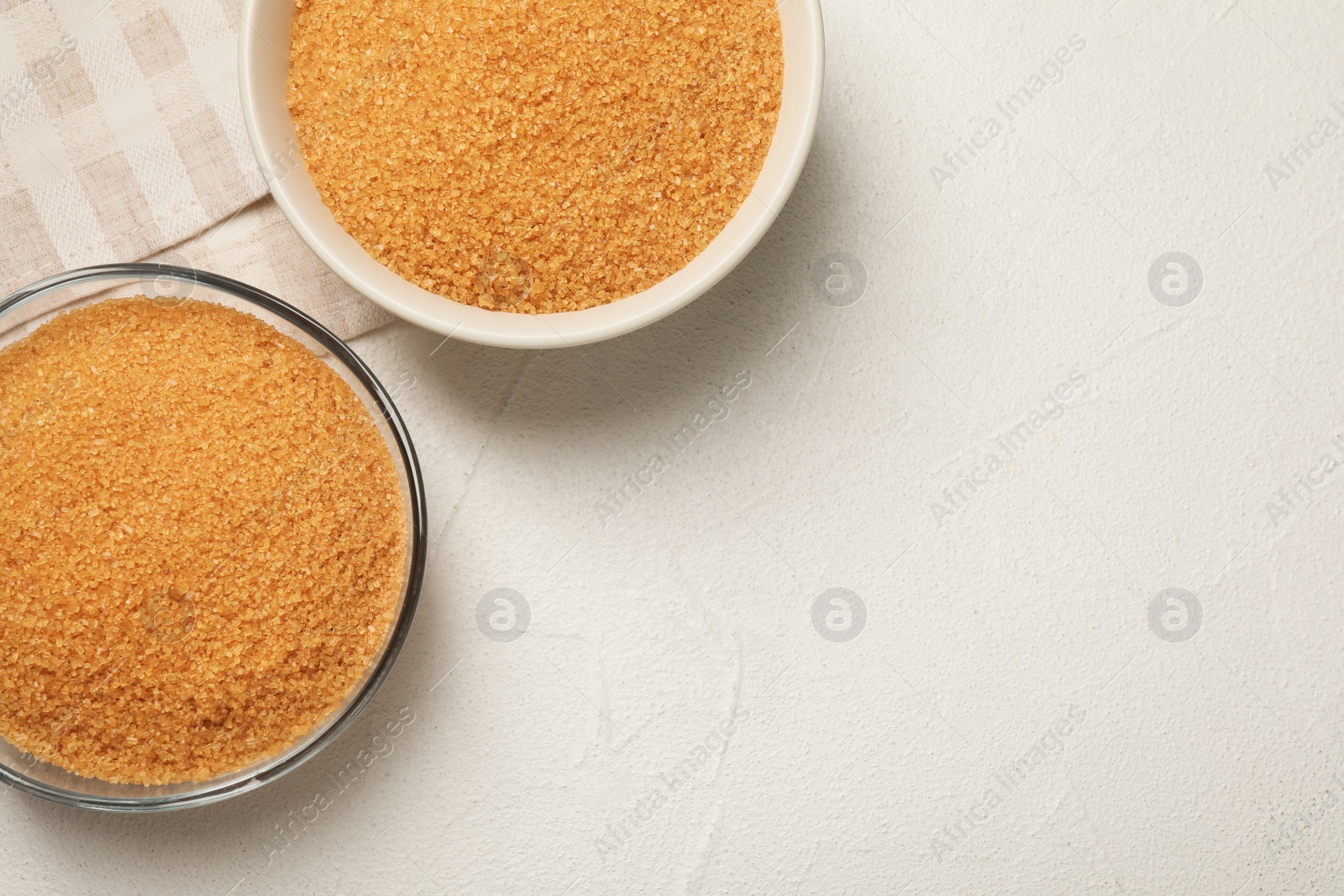 Photo of Brown sugar in bowls on white table, flat lay. Space for text