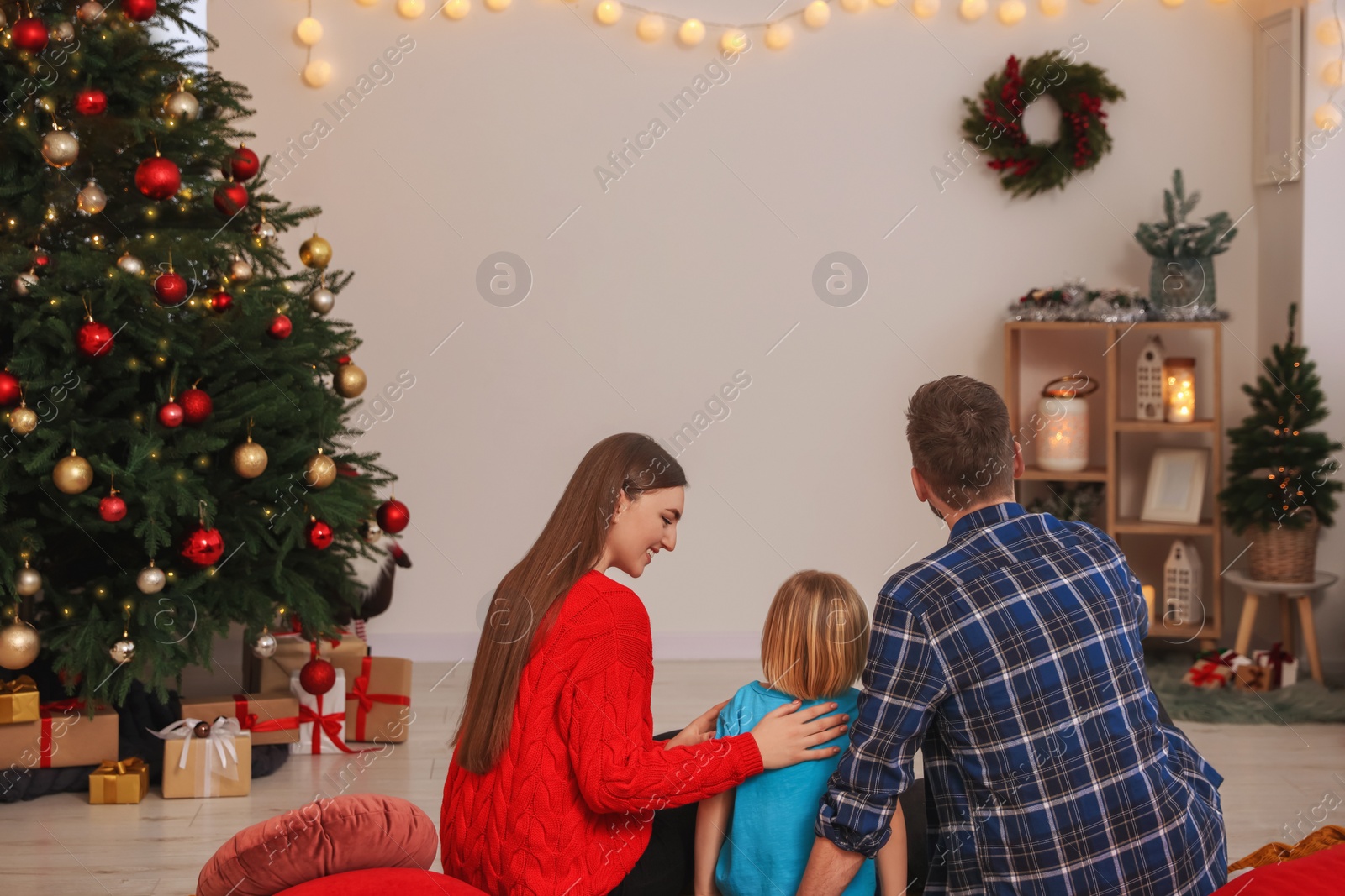 Photo of Happy family watching Christmas movie via projector in cosy room, back view. Winter holidays atmosphere