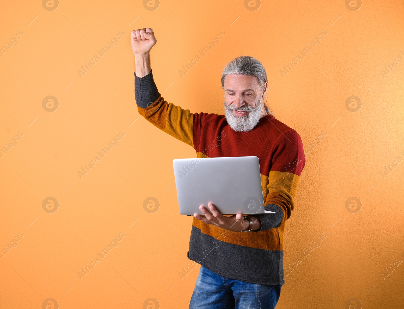 Photo of Portrait of handsome mature man with laptop on color background