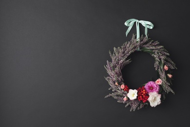 Photo of Beautiful autumnal wreath with heather flowers hanging on black background. Space for text