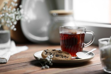 Photo of Cupfreshly brewed tea and delicious cookies on wooden table, space for text