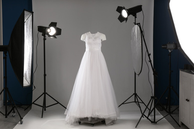 Beautiful clothes on ghost mannequin and professional lighting equipment in modern studio. Fashion photography