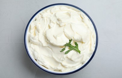 Bowl of tasty cream cheese and arugula on grey table, top view