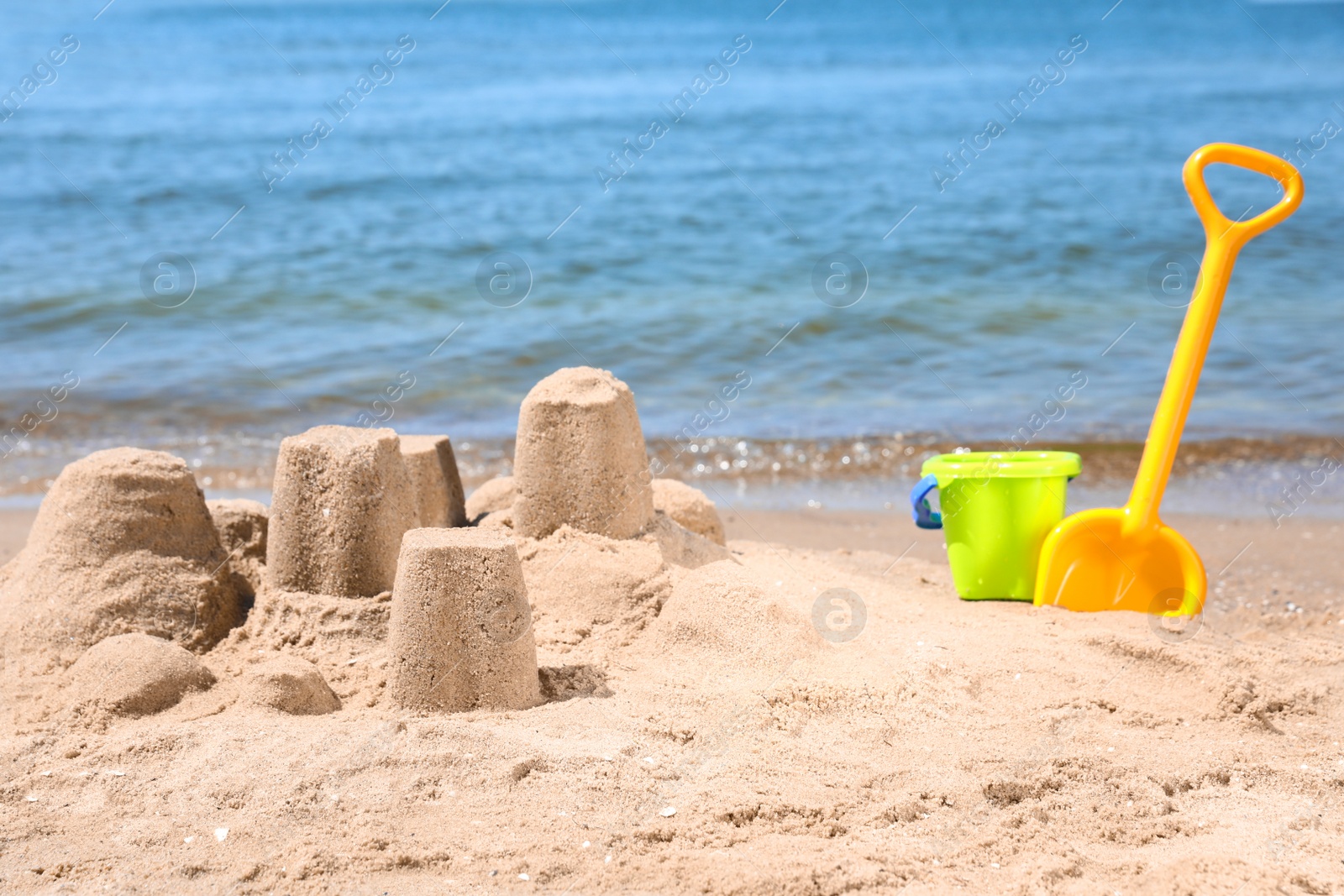 Photo of Little sand figures and plastic toys on beach near sea