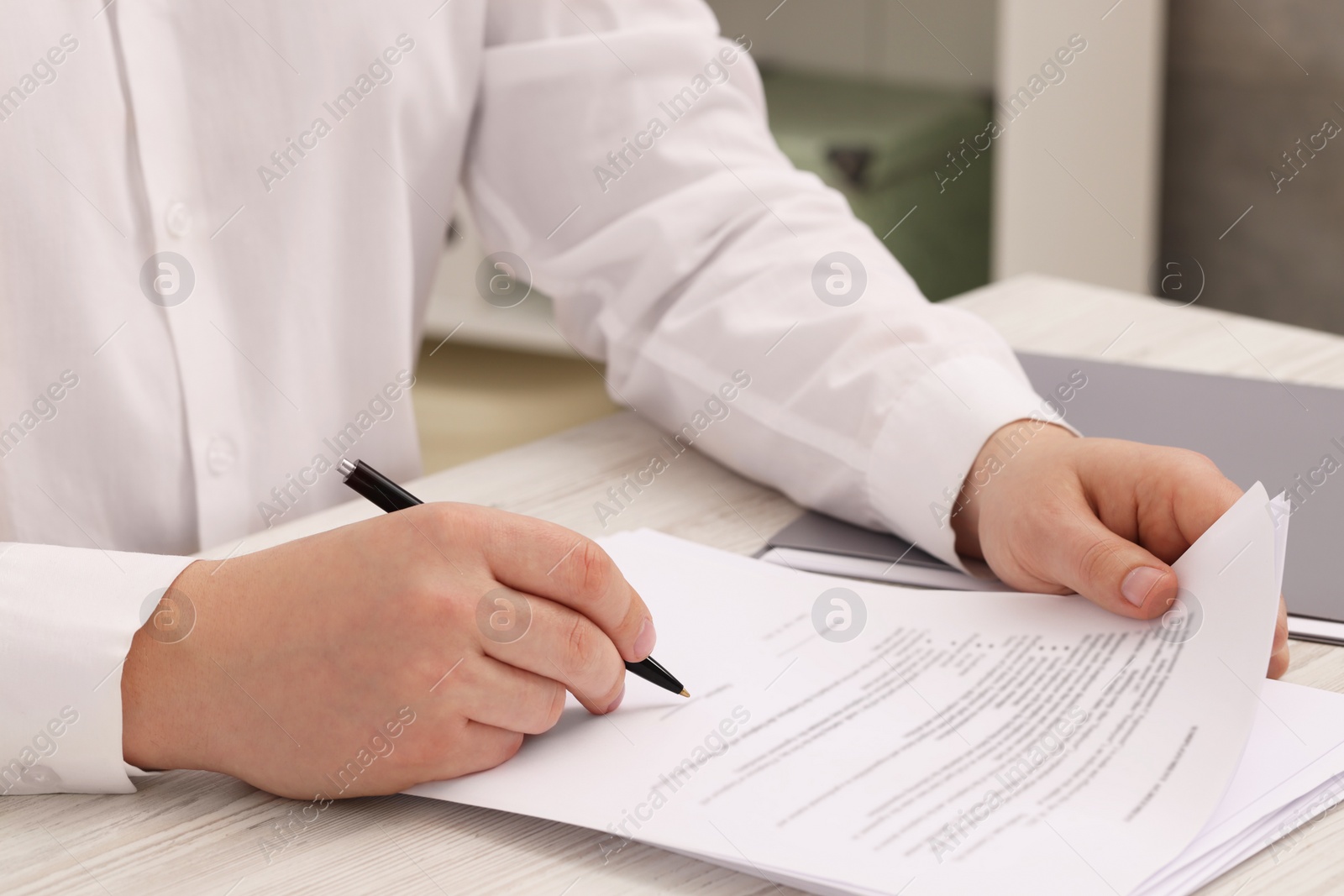 Photo of Man signing document at wooden table, closeup