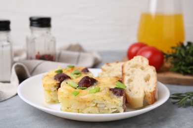 Photo of Tasty sausage casserole with green onion and bread on grey table, closeup